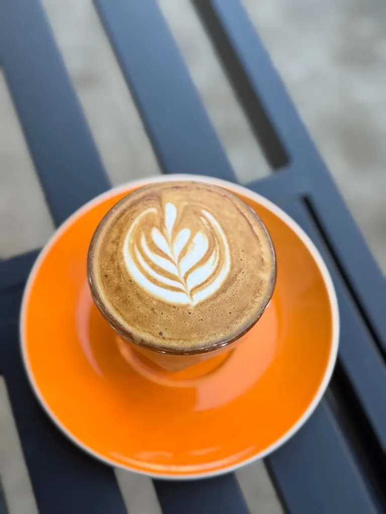 Flat white in a faceted glass on a wooden table