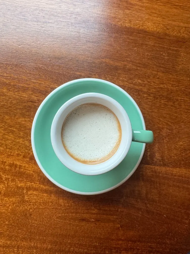 Cortado in a mint-green ceramic cup, top down