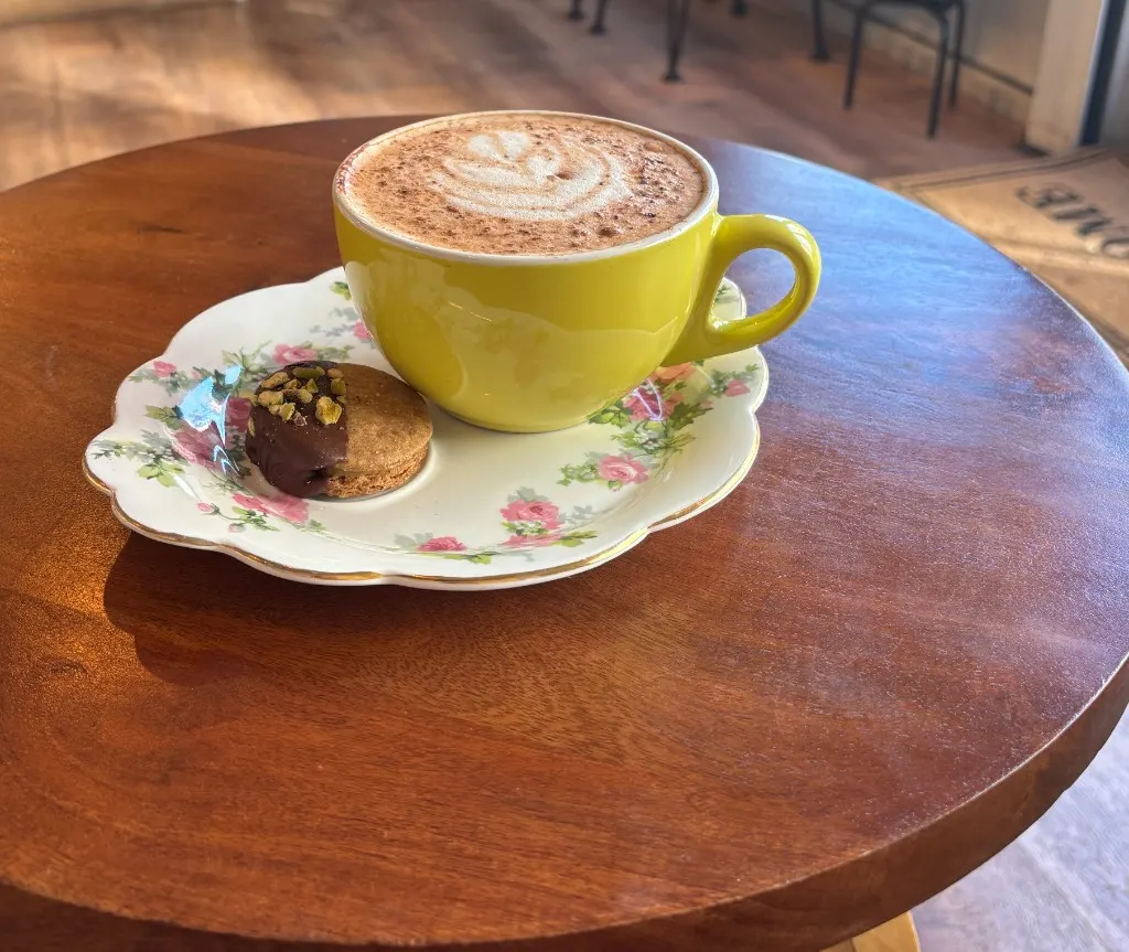 Latte with rosetta art beside a pot of pink kalanchoe