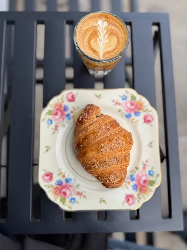 Latte rosetta in a white cup on an orange saucer